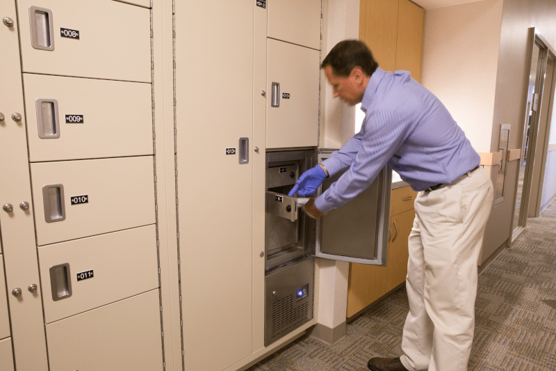 Deposit of refrigerated short term evidence at Central Marin Police Department, man is placing item in refrigerated evidence locker