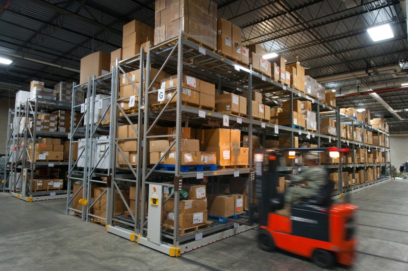 Heavy Duty mobile racking in Central Issue Facility, man on red pallet driver in a warehouse